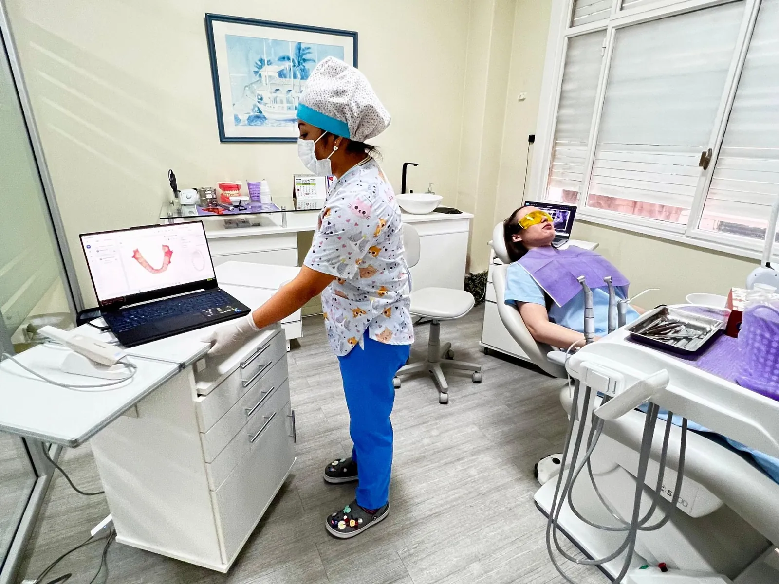 Odontóloga de Dental Ciudad mostrando un escaneo 3D en la computadora, con una paciente en el sillón